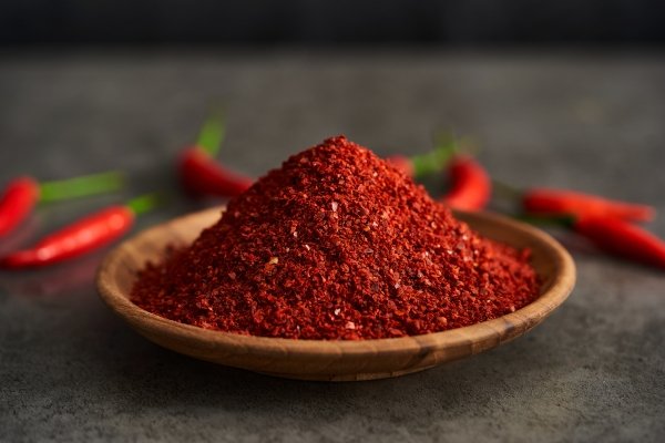 How to Identify Pure Red Chili Powder – natural red chili powder in a wooden bowl with whole chilies in the background