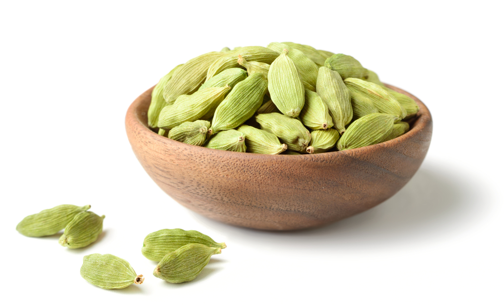Fresh green cardamom pods in wooden bowl, exported globally by Rudra Shakti Overseas.