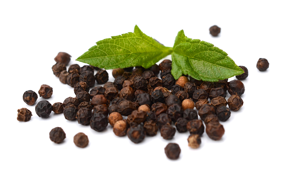 Black pepper with green leaf placed on a white background.