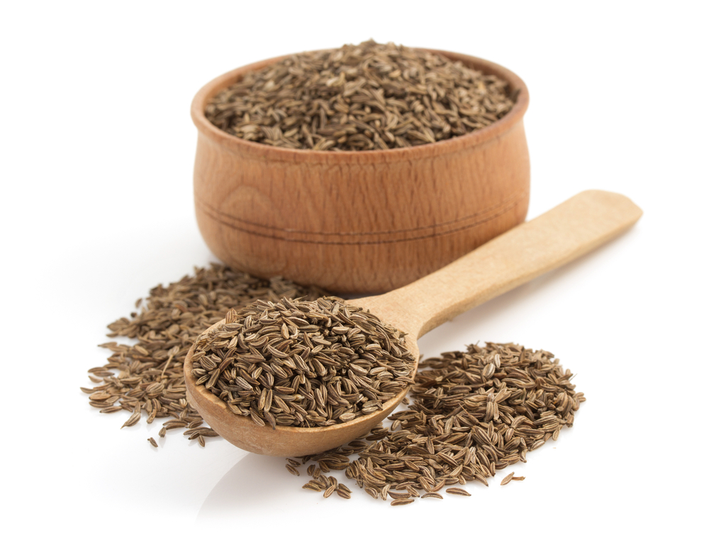 High-quality cumin seeds in wooden bowl and spoon, exported globally by Rudra Shakti Overseas.